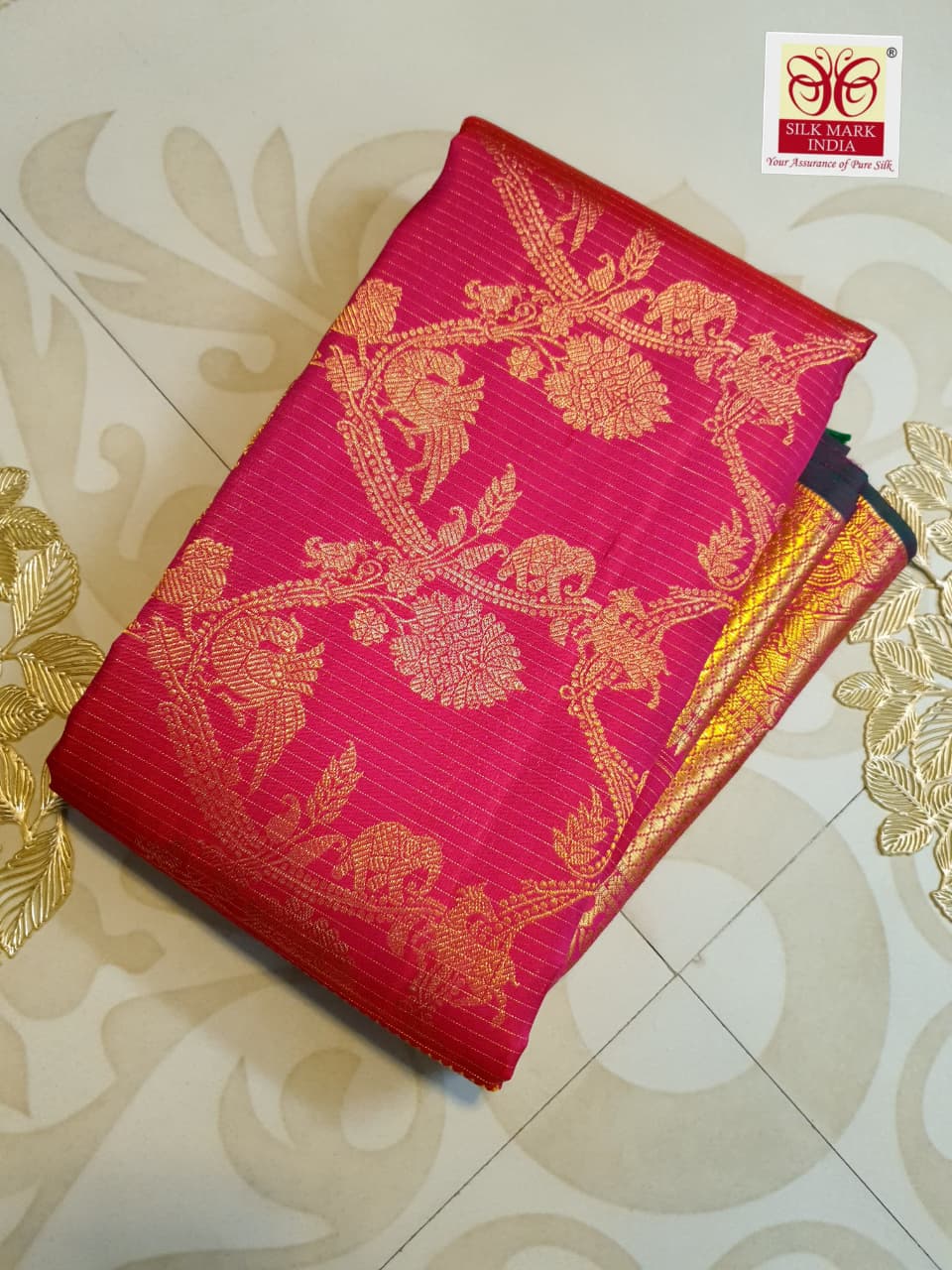 Close-up of pink silk saree with gold zari floral and animal motifs