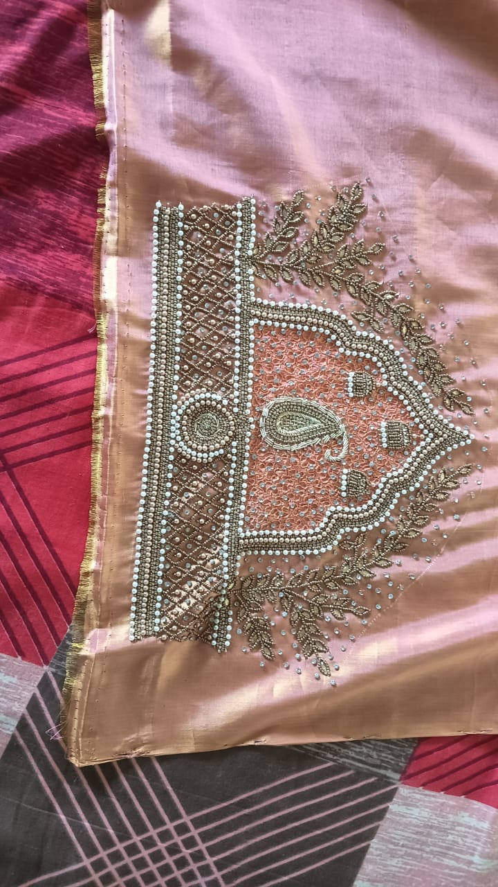 Detailed view of custom Maggham embroidery work on premium pink fabric, showcasing intricate hand-embroidered borders, leaf motifs, and beadwork on a traditional wooden embroidery frame