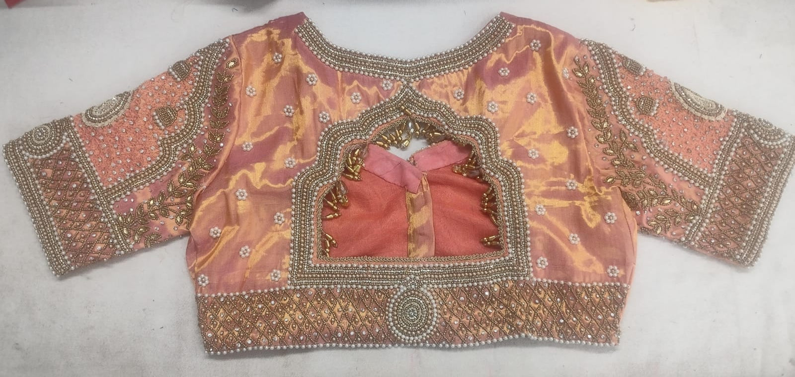 Detailed view of custom Maggham embroidery work on premium pink fabric, showcasing intricate hand-embroidered borders, leaf motifs, and beadwork on a traditional wooden embroidery frame