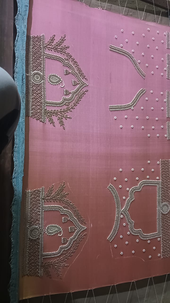 Detailed view of custom Maggham embroidery work on premium pink fabric, showcasing intricate hand-embroidered borders, leaf motifs, and beadwork on a traditional wooden embroidery frame