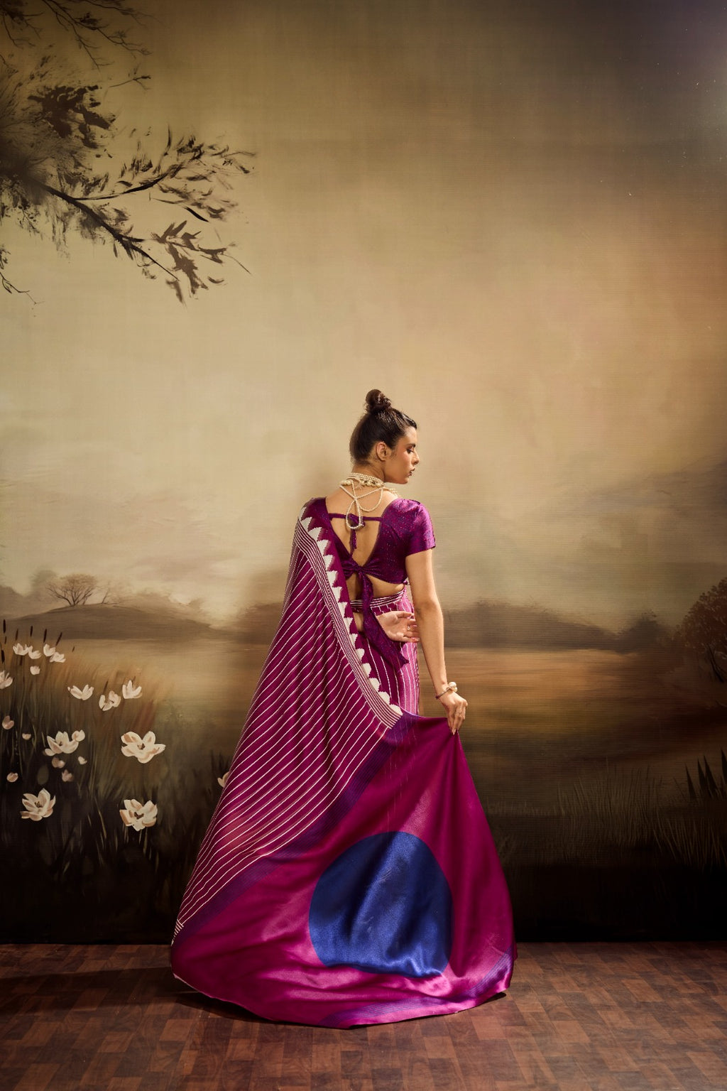 A vibrant magenta modal silk saree with white vertical pinstripes, a large royal blue circular design on the pallu, and a matching patterned blouse piece.