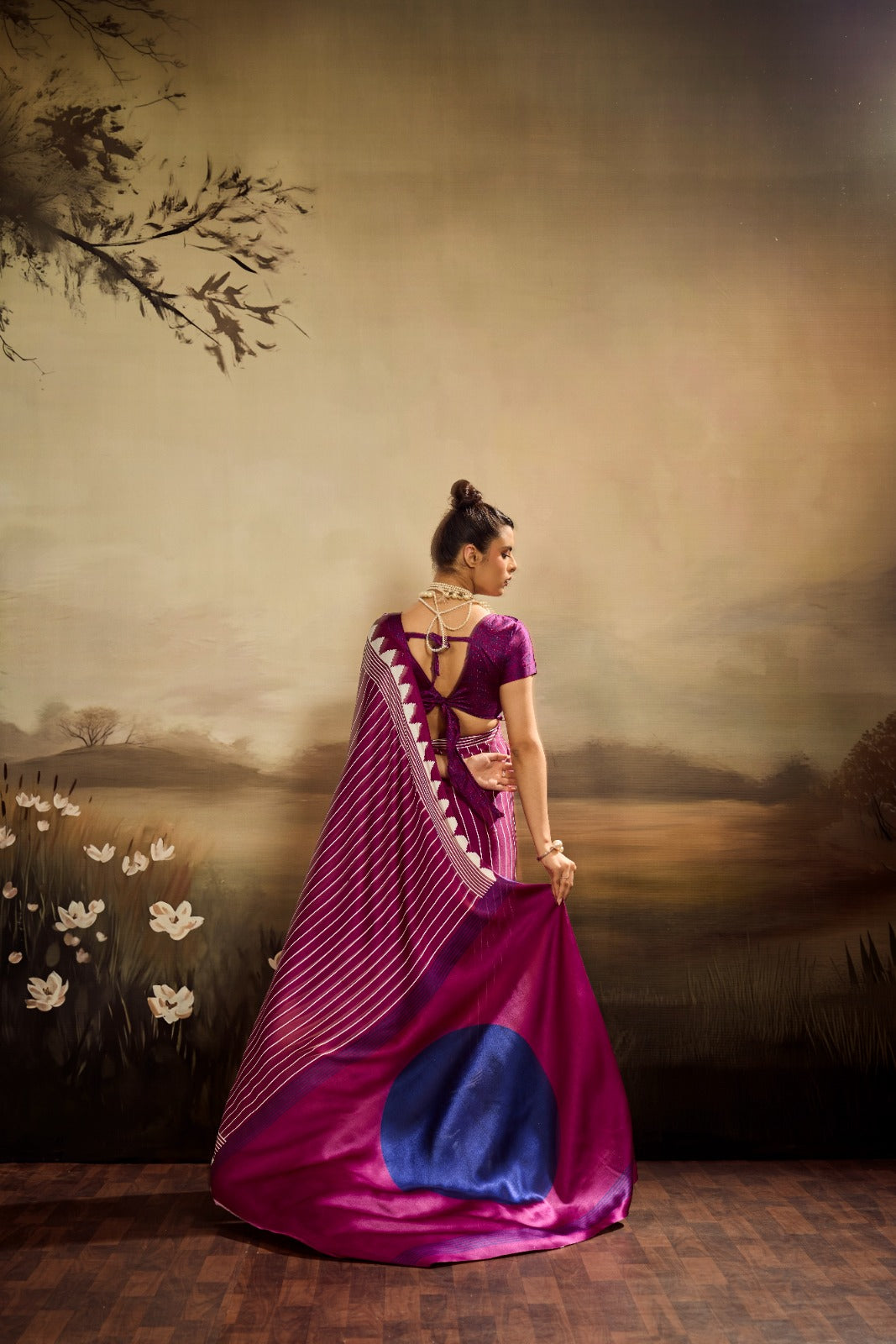 A vibrant magenta modal silk saree with white vertical pinstripes, a large royal blue circular design on the pallu, and a matching patterned blouse piece.