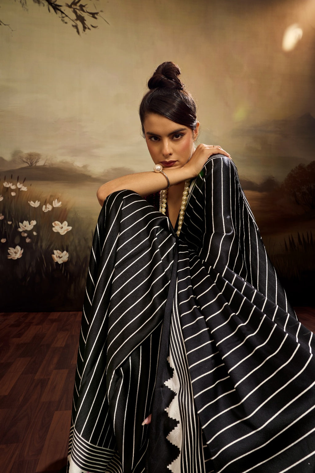 Jet black modal silk saree with white vertical pinstripes, a large bright pink circular motif on the pallu, and a matching patterned blouse piece.