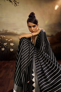 Jet black modal silk saree with white vertical pinstripes, a large bright pink circular motif on the pallu, and a matching patterned blouse piece.