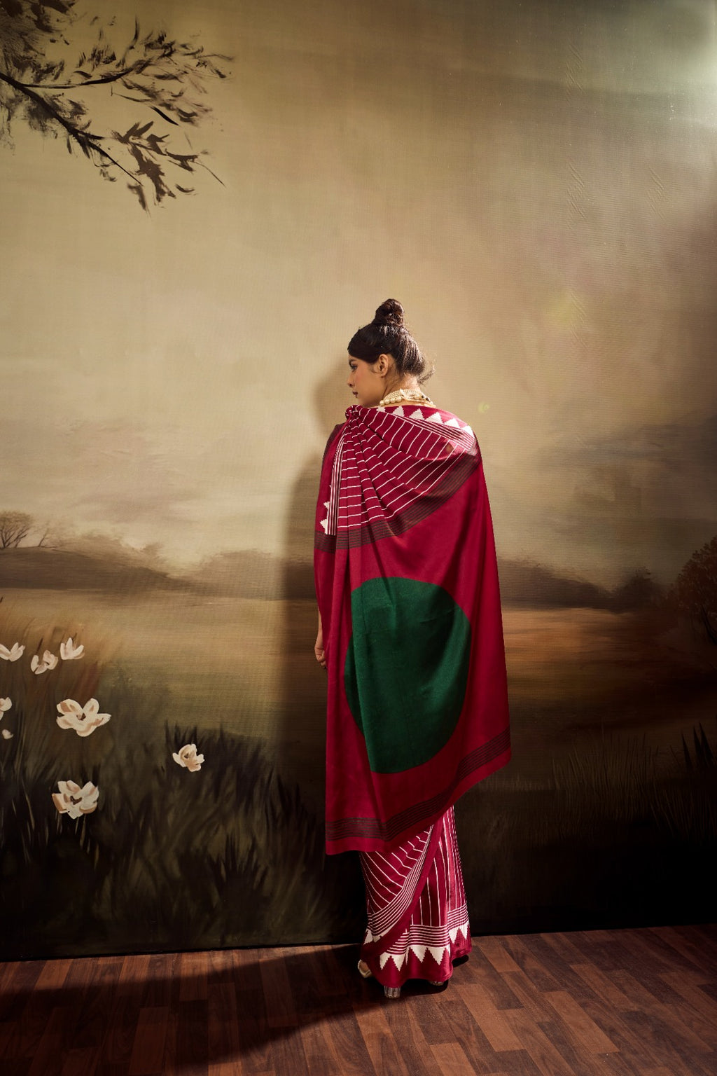 A maroon modal silk saree featuring uniform white vertical stripes, a solid green circular accent on the pallu, and a sharp white triangular border.