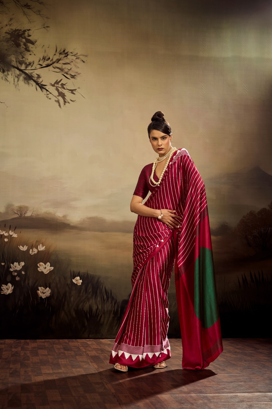 A maroon modal silk saree featuring uniform white vertical stripes, a solid green circular accent on the pallu, and a sharp white triangular border.