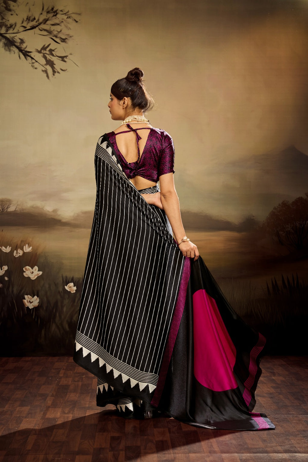 Jet black modal silk saree with white vertical pinstripes, a large bright pink circular motif on the pallu, and a matching patterned blouse piece.