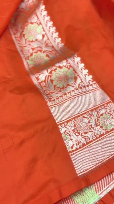 A vibrant orange handloom Banarasi Katan silk saree with an intricate all-over grid pattern and multicolored Meenakari floral motifs, featuring a heavy gold zari border and pallu.