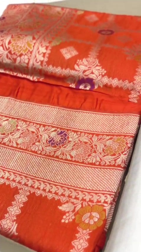 A vibrant orange handloom Banarasi Katan silk saree with an intricate all-over grid pattern and multicolored Meenakari floral motifs, featuring a heavy gold zari border and pallu.