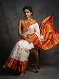White and red Pochampally handloom ikat silk saree with Silk Mark certification, featuring all-over buttas and a rich zari border.