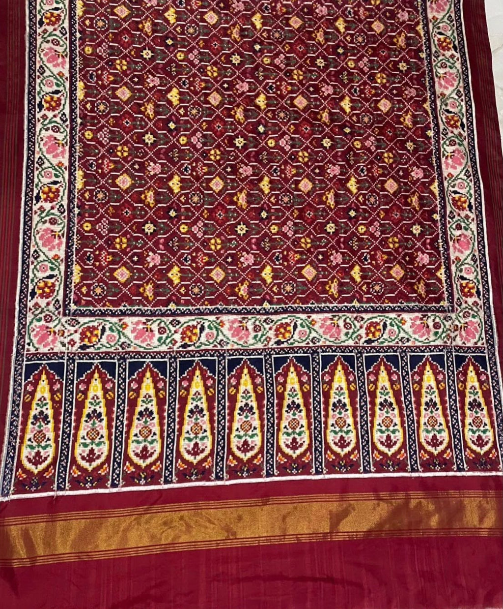 An exquisite maroon Patan Patola double ikat pure mulberry silk saree featuring intricate traditional geometric motifs, rich contrasting borders, and a masterpiece pallu dyed using natural vegetable colors.