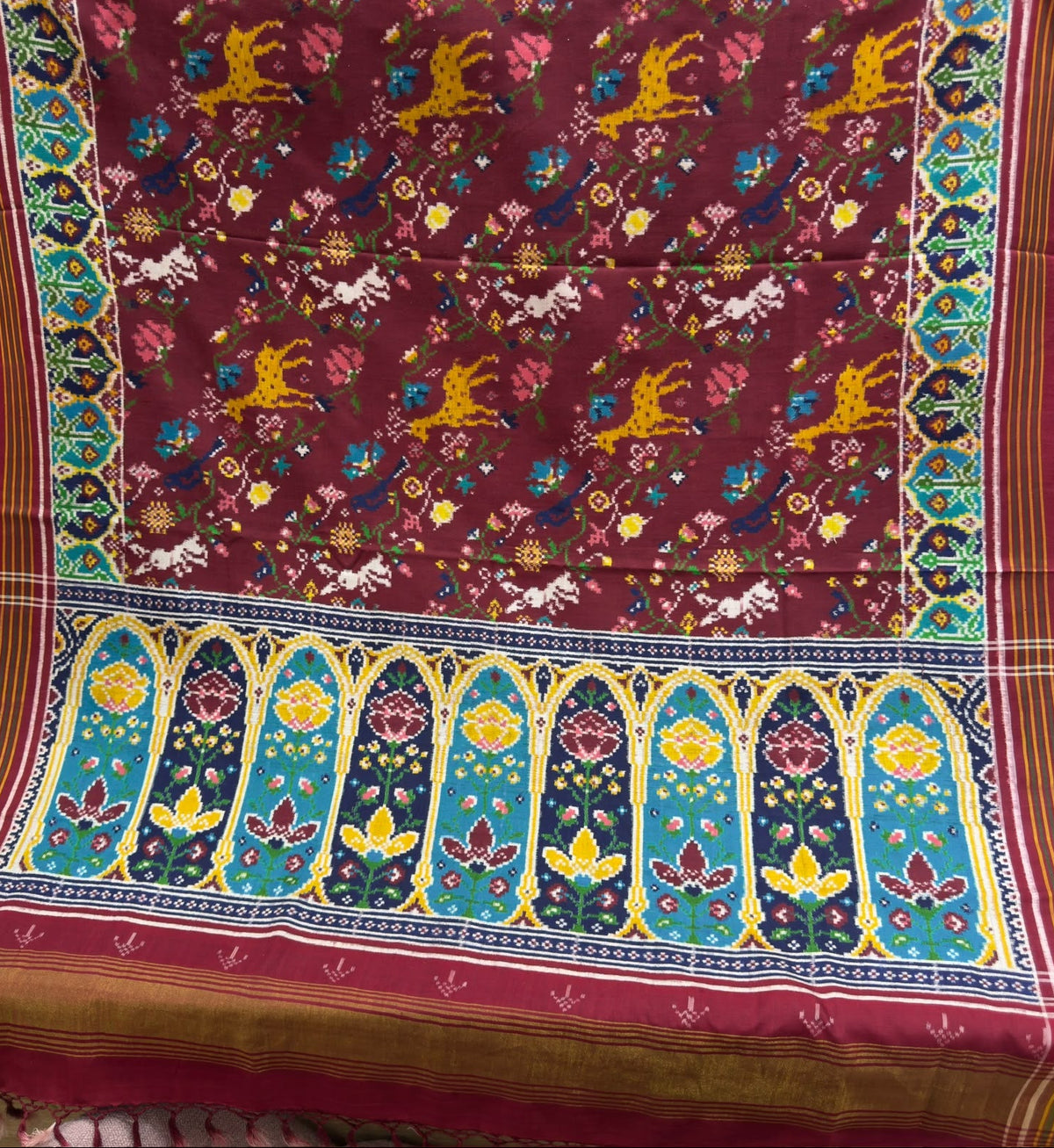 Maroon Patan Patola pure mulberry silk saree featuring a vegetable-dyed jungle design with intricate double ikat weaving and ornate architectural border motifs.