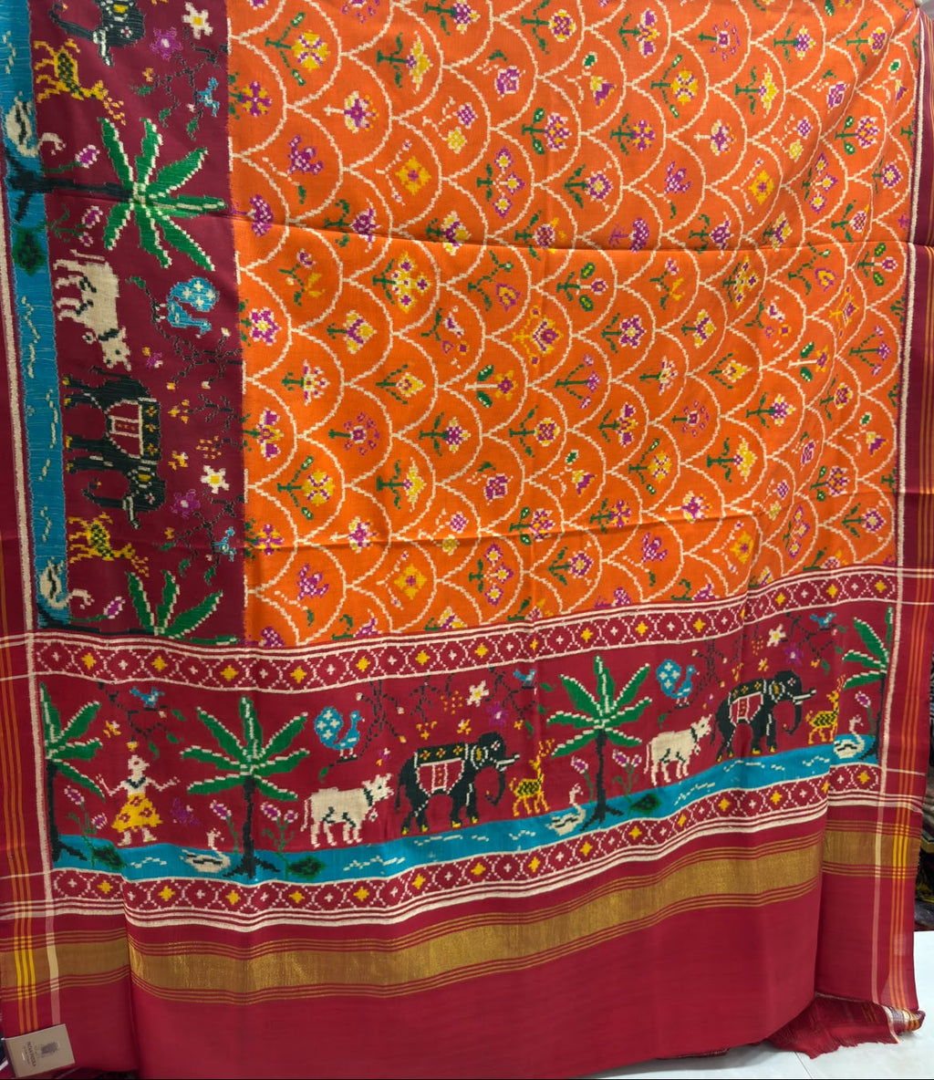 Vibrant orange Patan Patola pure mulberry silk saree featuring a complex double ikat wave and scale pattern with contrasting maroon pallu and border depicting traditional animal and tree motifs.