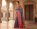 A magnificent blue Patan Patola double ikat pure mulberry silk saree featuring intricate red and white geometric motifs, a striking rich red pallu with traditional tree designs, and contrasting borders.