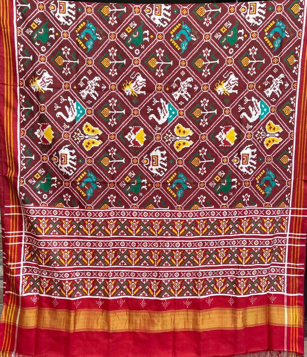 Model wearing a rustic red Patan Patola pure mulberry silk saree featuring an elaborate double ikat figurative design with traditional borders and pallu.
