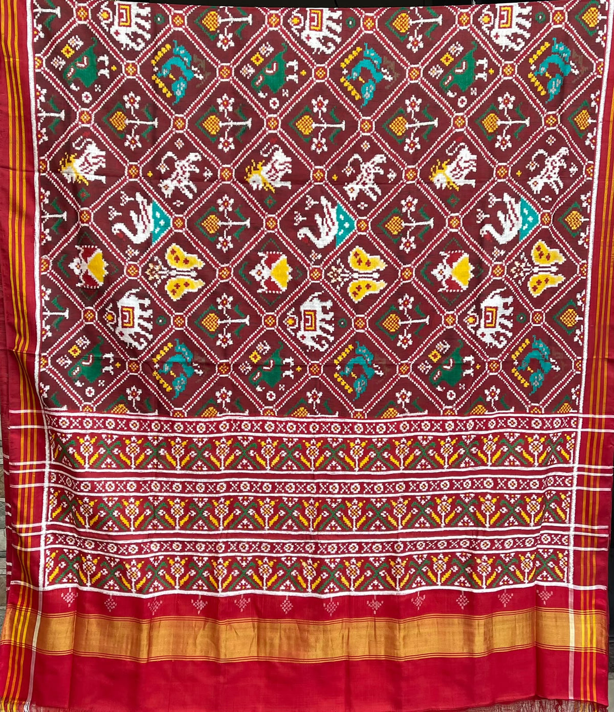 Model wearing a rustic red Patan Patola pure mulberry silk saree featuring an elaborate double ikat figurative design with traditional borders and pallu.