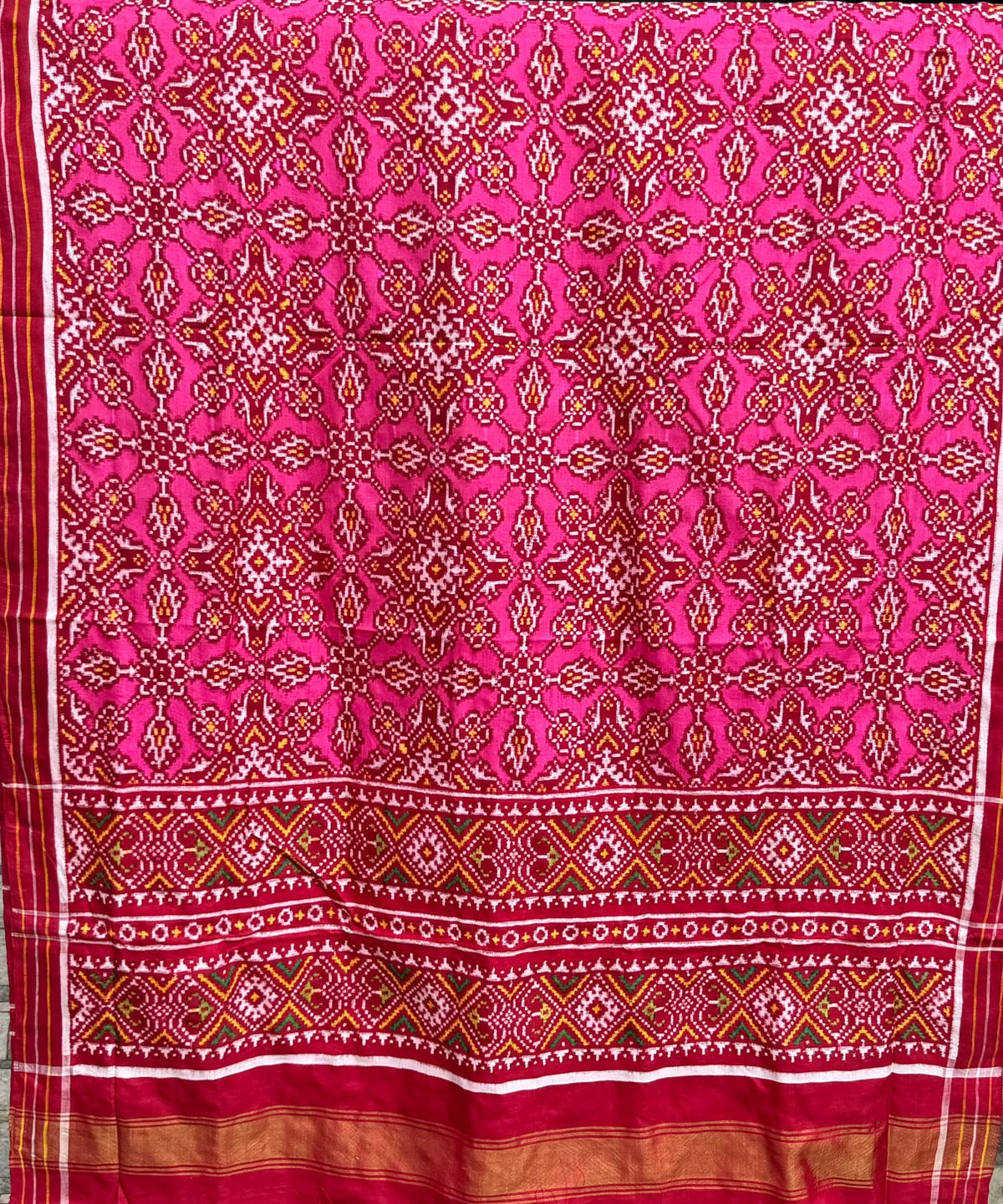 Dark pink Patan Patola pure mulberry silk saree featuring an intricate geometric double ikat lattice design with a matching patterned pallu and traditional borders.