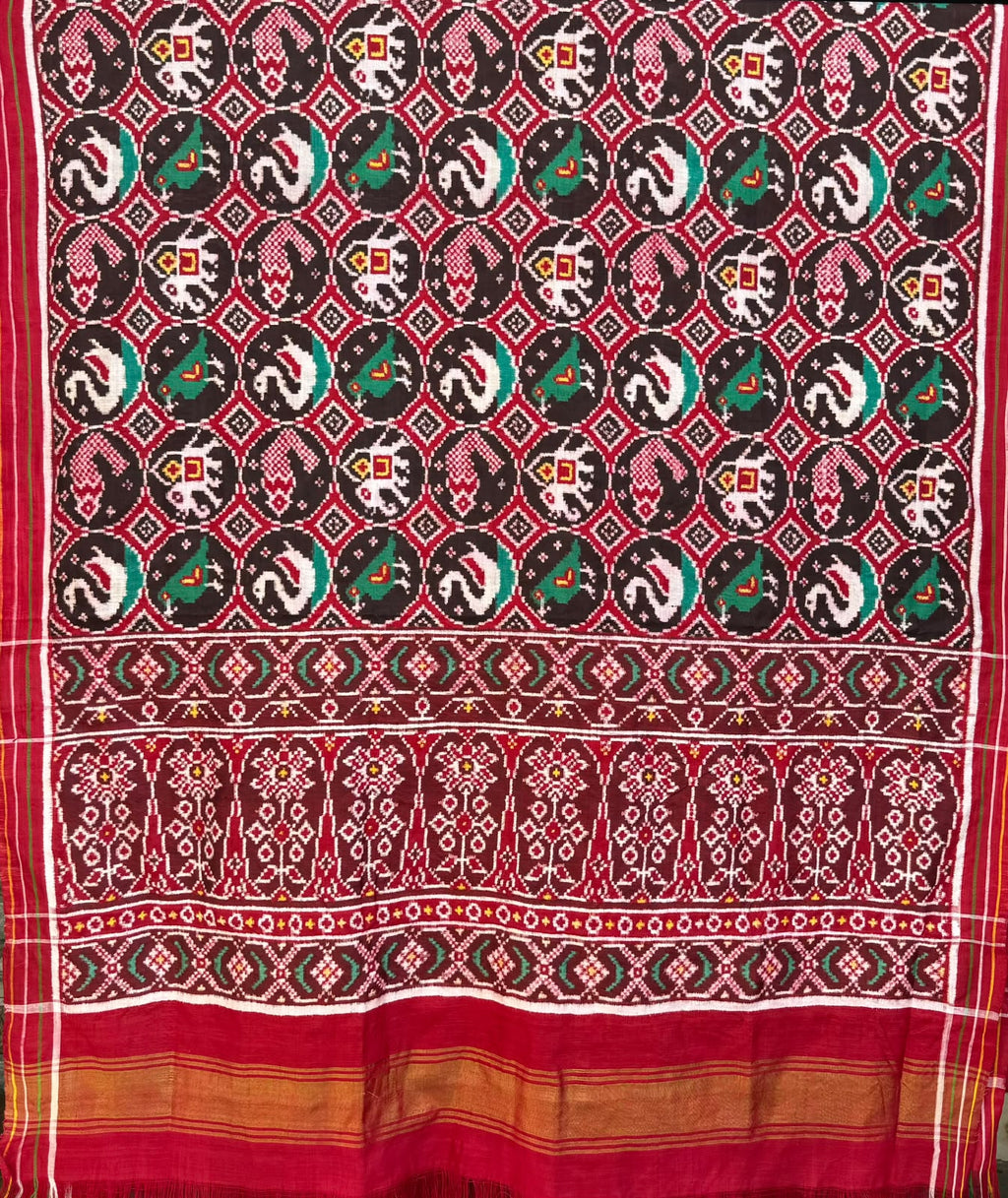 Model wearing a rustic red Patan Patola pure mulberry silk saree featuring an elaborate double ikat figurative design with traditional borders and pallu.