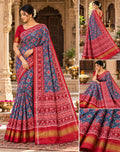 A magnificent blue Patan Patola double ikat pure mulberry silk saree featuring intricate red and white geometric motifs, a striking rich red pallu with traditional tree designs, and contrasting borders.