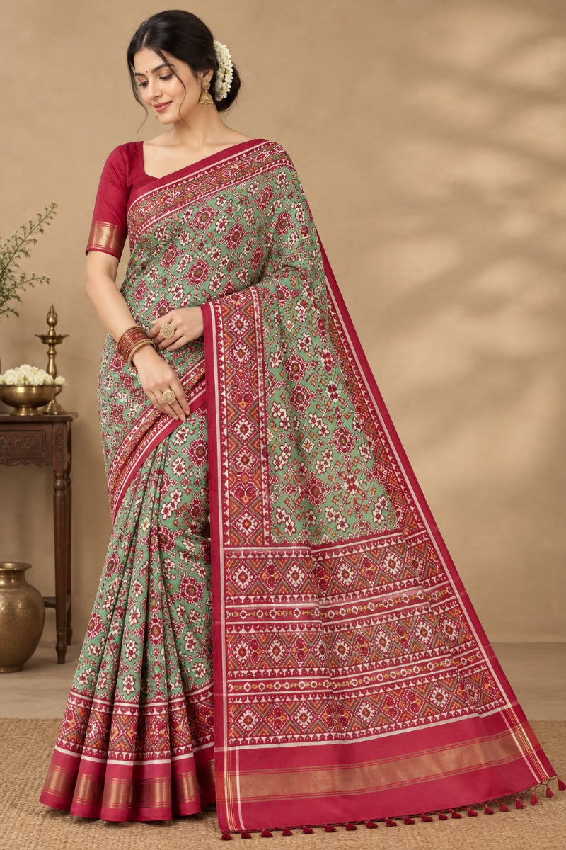 A striking green Patan Patola double ikat pure mulberry silk saree featuring intricate red and white geometric patterns, ornate contrasting borders, and a magnificent rich red pallu dyed using natural vegetable colors.