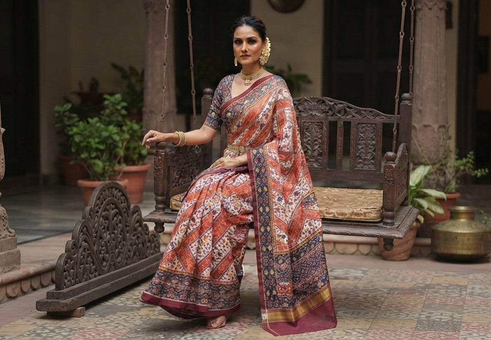 A magnificent coral Patan Patola double ikat pure mulberry silk saree featuring vibrant diagonal multi-colored geometric patterns, intricate contrasting borders, and a rich traditional pallu dyed with natural vegetable colors.