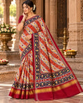 A magnificent coral Patan Patola double ikat pure mulberry silk saree featuring vibrant diagonal multi-colored geometric patterns, intricate contrasting borders, and a rich traditional pallu dyed with natural vegetable colors.
