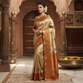 A close-up of a luxurious gold tissue Kanchipuram silk saree with vibrant rust orange borders and intricate Meenakari floral brocade weaving.