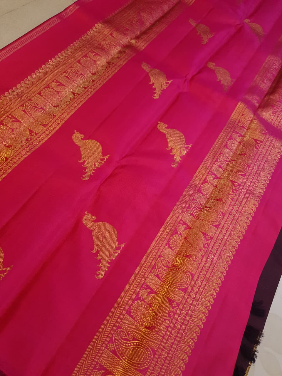 A certified magenta Kanchipuram handloom 3G pure gold borderless silk saree showcasing its rich color and lustrous weave.