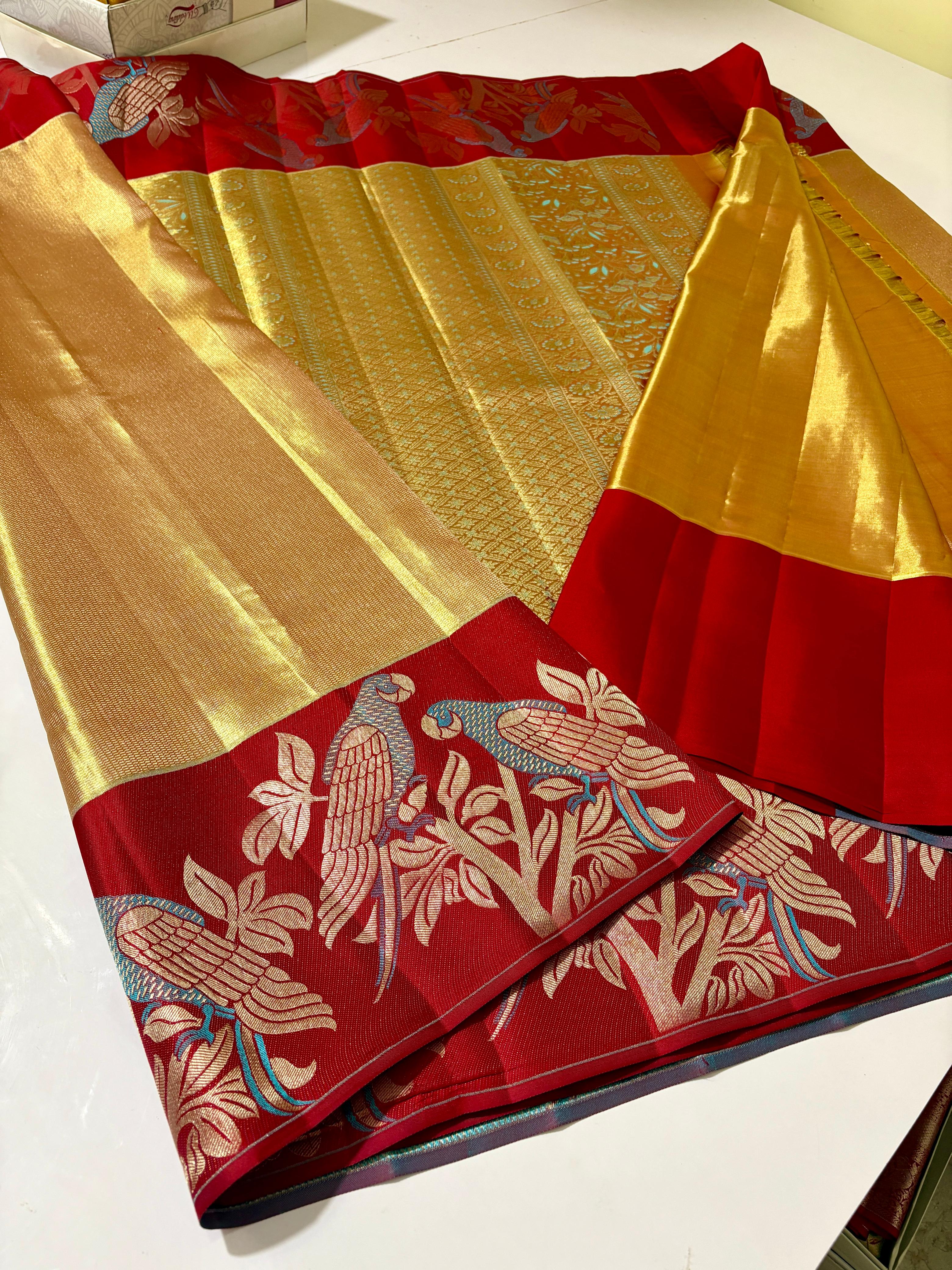 Gold Kanchipuram 1G tissue silk saree with a bold red border featuring intricate meenakari parrot motifs, styled for a traditional wedding look.