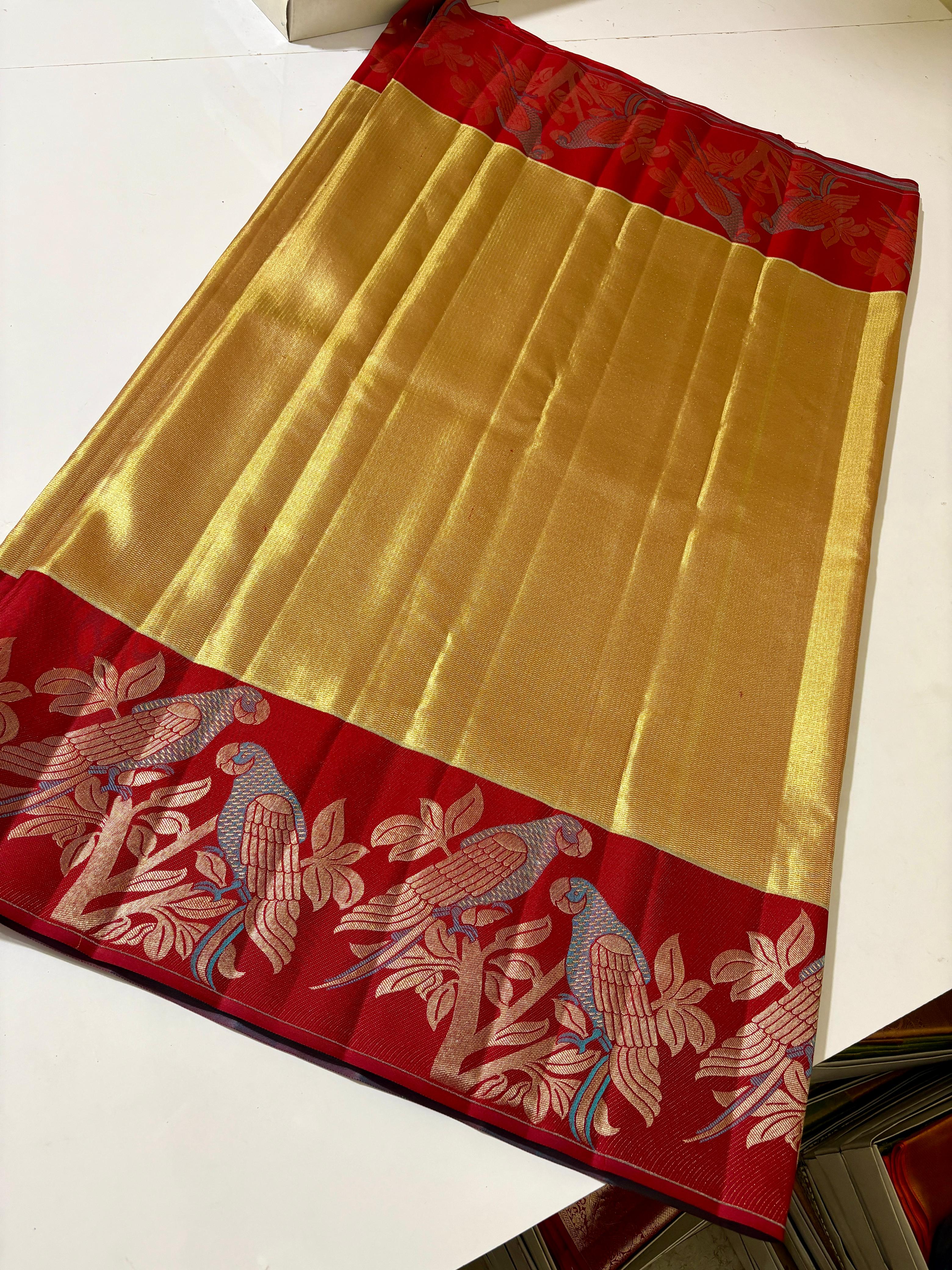 Gold Kanchipuram 1G tissue silk saree with a bold red border featuring intricate meenakari parrot motifs, styled for a traditional wedding look.