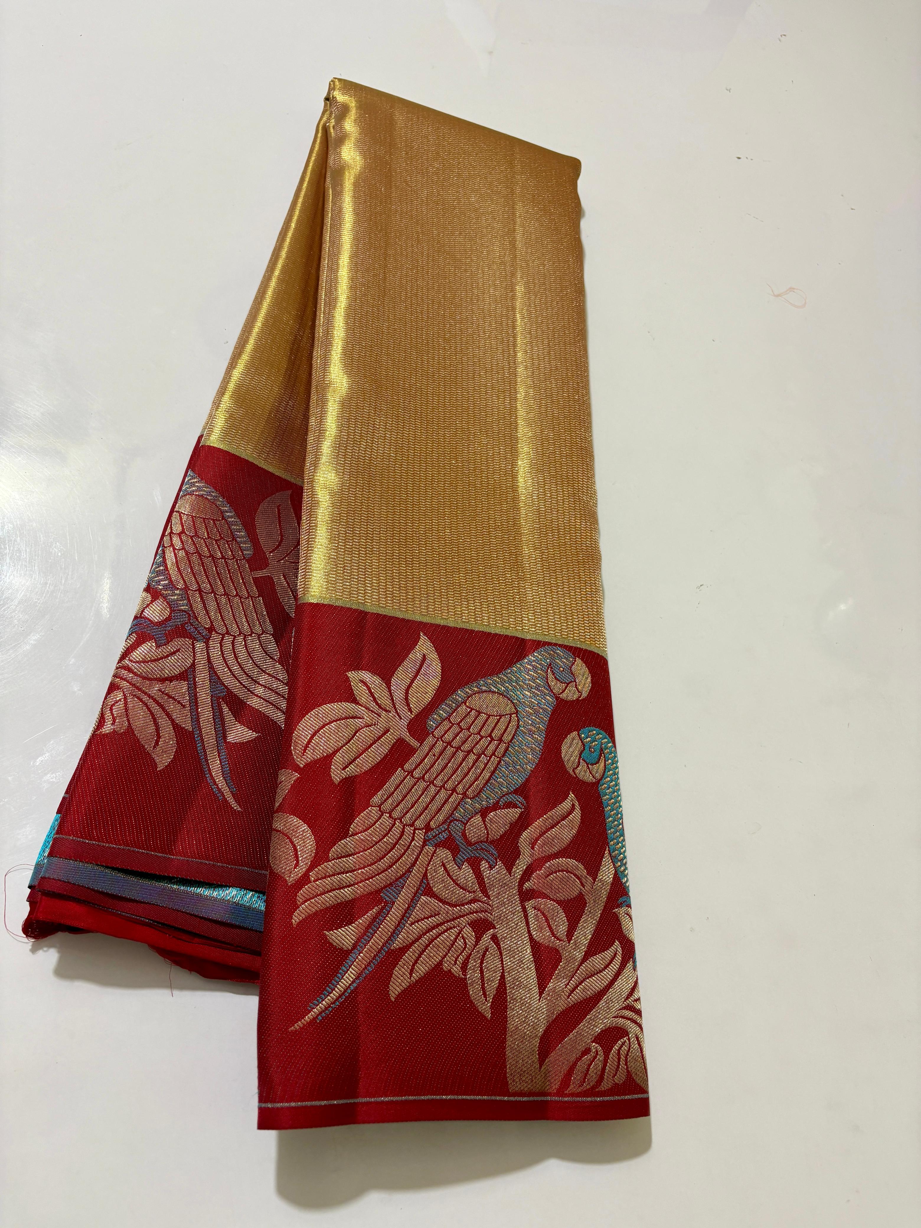 Gold Kanchipuram 1G tissue silk saree with a bold red border featuring intricate meenakari parrot motifs, styled for a traditional wedding look.