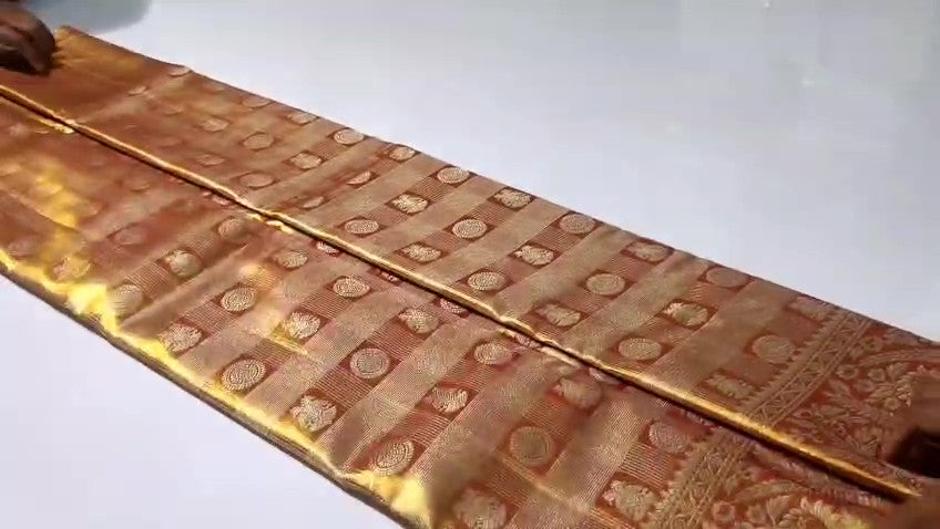 Copper Kanchipuram Handloom Tissue Brocade Silk Meenakari Saree displayed in a neat fold showcasing its rich gold zari and floral weave details.