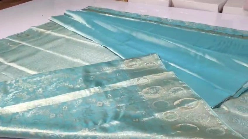 A close-up of light aqua blue fabric with a subtle woven circular pattern, laid out on a white surface.