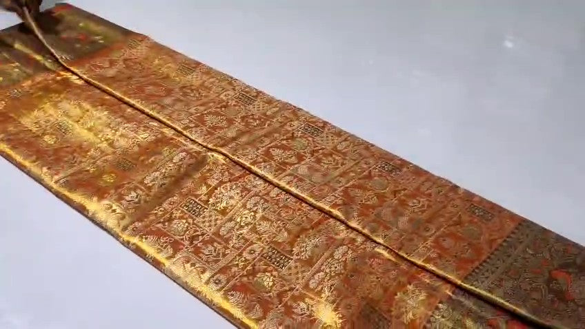 Orange Kanchipuram handloom 1G tissue silk saree with intricate meenakari brocade work and metallic zari borders, styled for a traditional South Indian wedding.