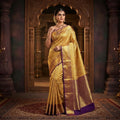 Elegant model wearing a gold Kanchipuram tissue brocade silk bridal saree with a rich violet border and intricate traditional zari pallu.