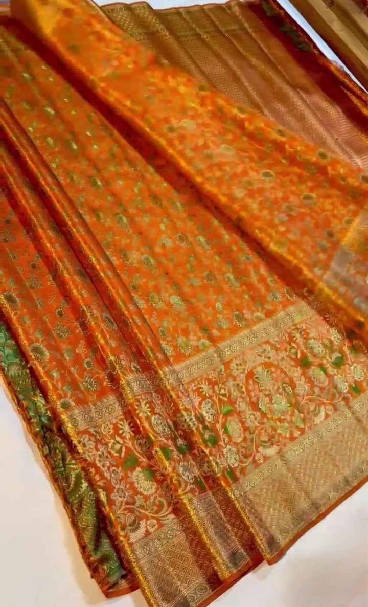 Orange Kanchipuram handloom double warp tissue brocade silk saree featuring intricate Meenakari floral patterns and a rich golden zari border.