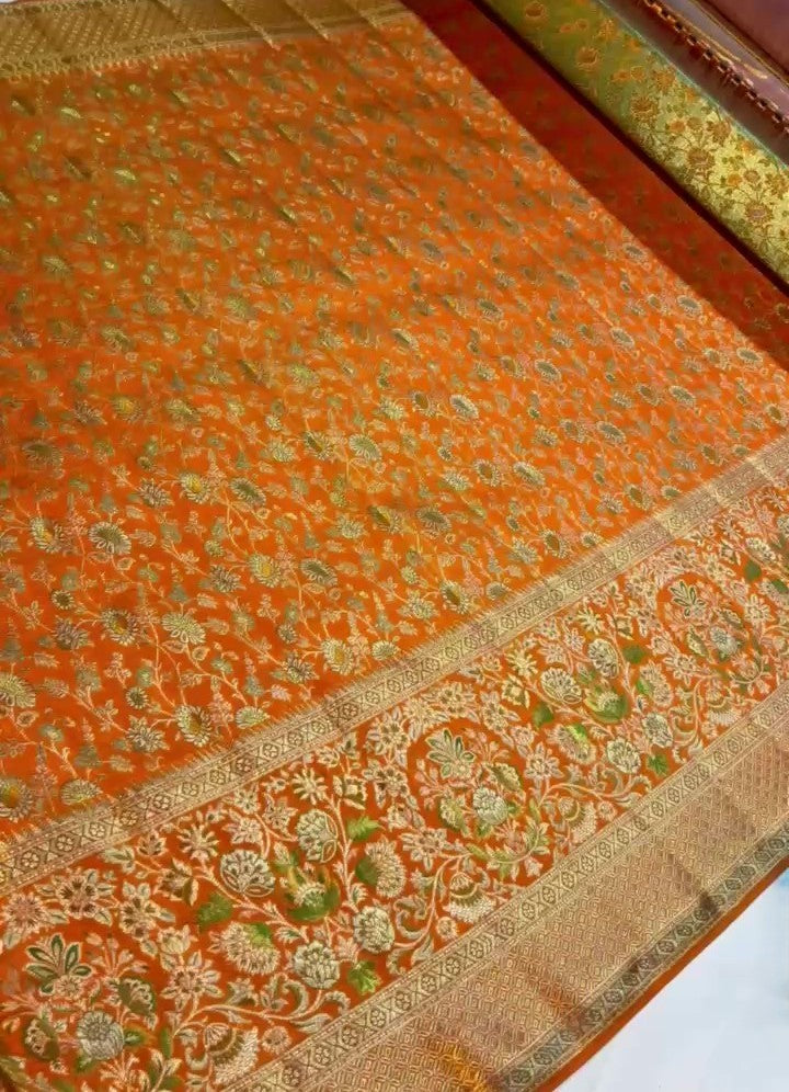 Orange Kanchipuram handloom double warp tissue brocade silk saree featuring intricate Meenakari floral patterns and a rich golden zari border.