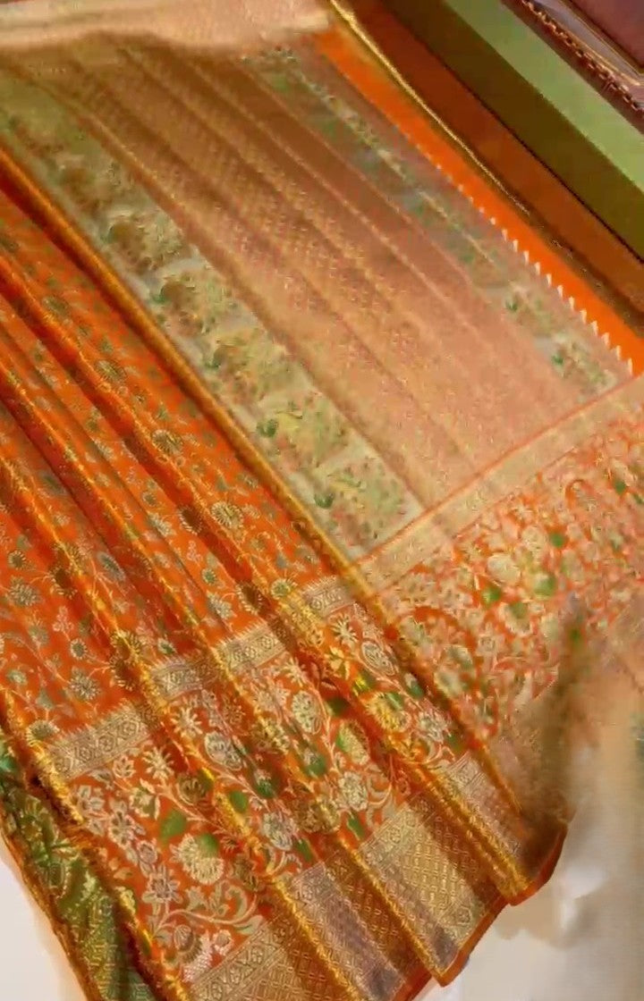 Orange Kanchipuram handloom double warp tissue brocade silk saree featuring intricate Meenakari floral patterns and a rich golden zari border.
