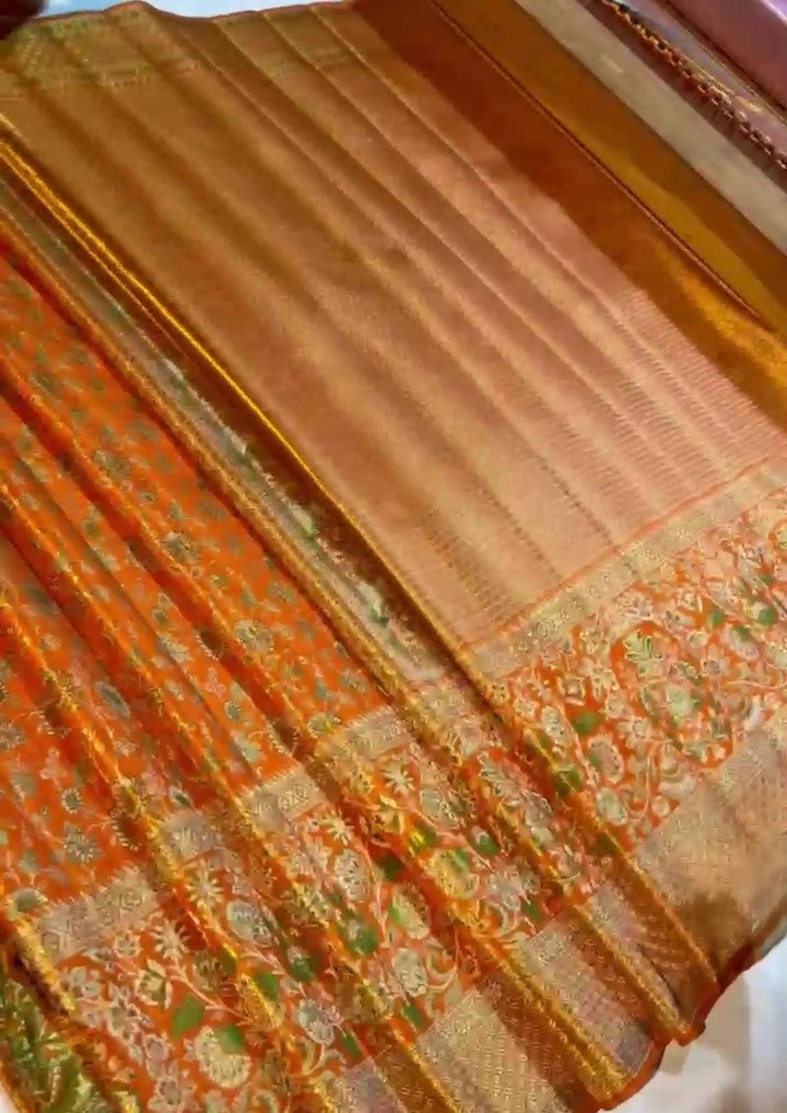 Orange Kanchipuram handloom double warp tissue brocade silk saree featuring intricate Meenakari floral patterns and a rich golden zari border.