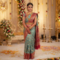 South Indian bride in a decorated wedding hall wearing a Turquoise Kanchipuram Handloom 1G Tissue Brocade Meenakari Silk Saree.