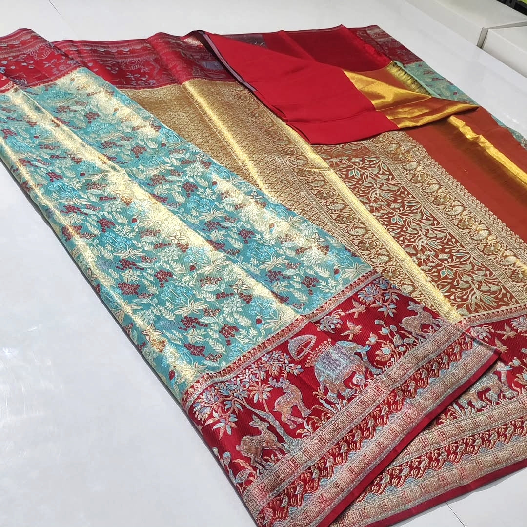 A traditional Indian silk saree with a turquoise blue body, red borders, and intricate gold zari embroidery, laid out on a white surface.