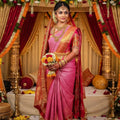 A bride wearing a luxurious Rani Pink Kanchipuram handloom double warp tissue brocade silk saree with intricate Kalyana Pallakku motifs and a grand rich border.