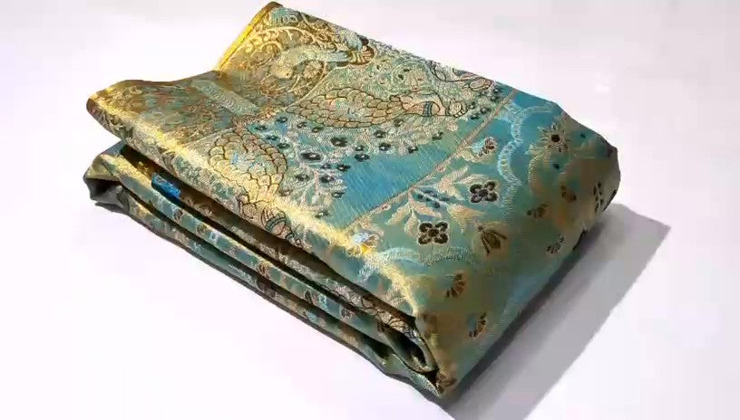 Radiant turquoise Kanchipuram handloom tissue brocade silk saree adorned with intricate multicolored Meenakari weaving and pure zari work.