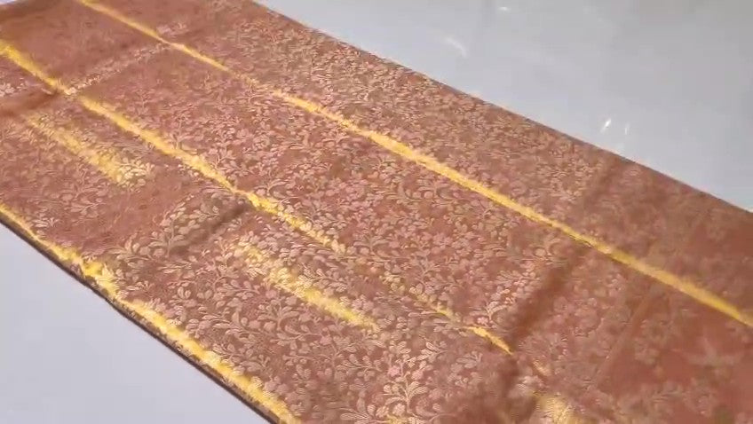 Peach Kanchipuram handloom tissue brocade silk bridal saree featuring an intricate all-over gold woven floral design and traditional zari borders.