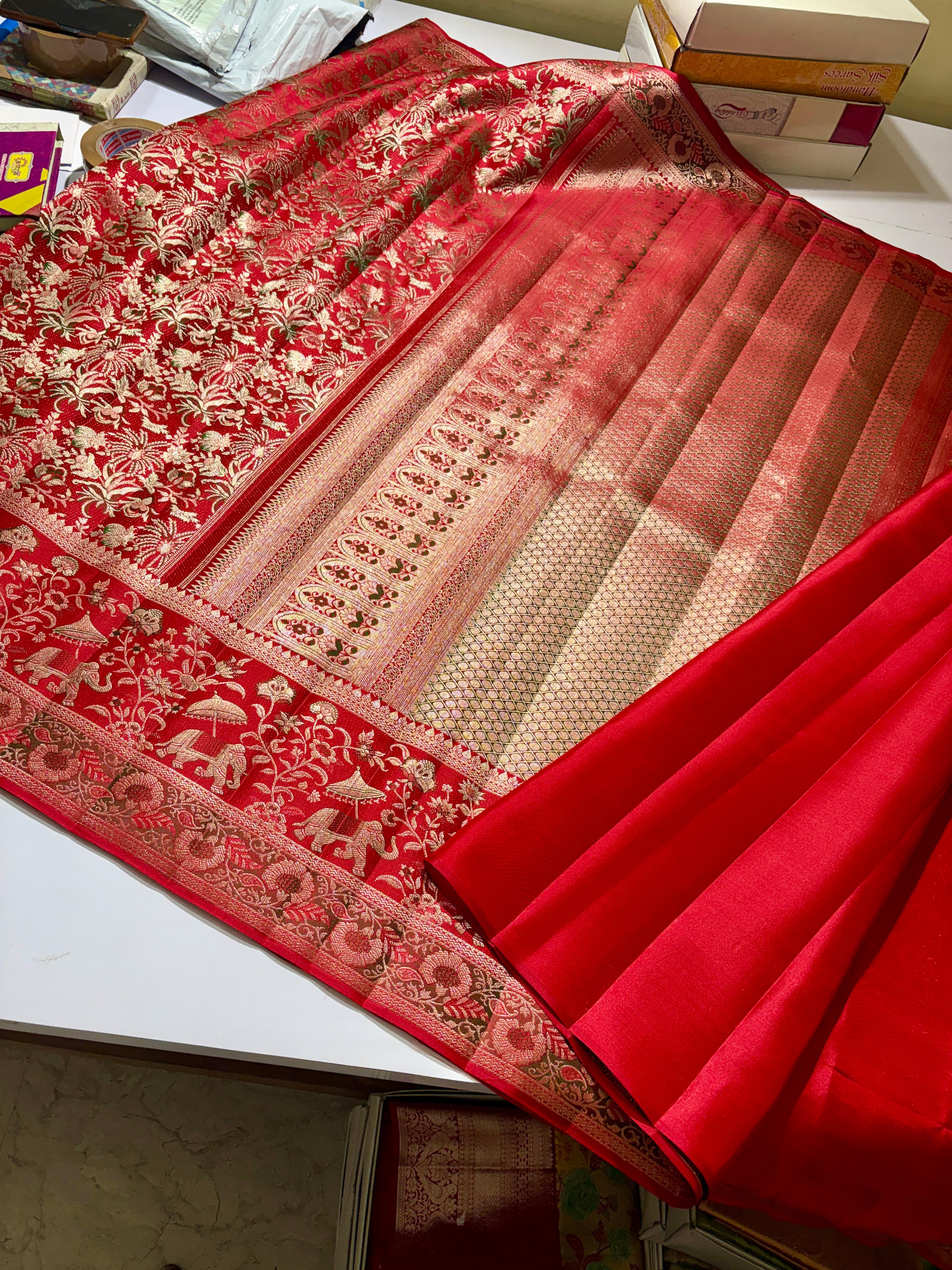 Vibrant red Kanchipuram handloom silk saree featuring detailed 1G gold brocade and multicolored Resham Meenakari work including elephant and floral vine patterns.