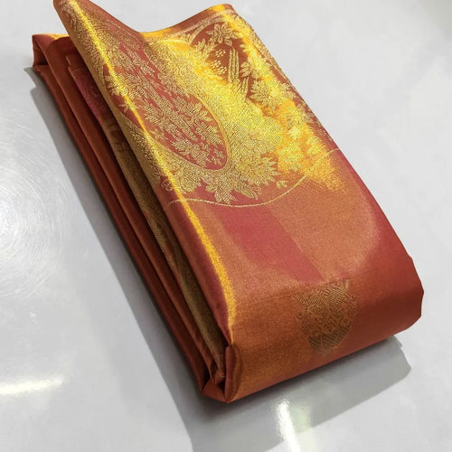 A close-up of a luxurious burnt orange Kanchipuram tissue silk saree with intricate gold brocade weaving, authentic Silk Mark certification, and a shimmering metallic finish.