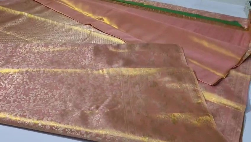 A close-up view of a Dusty Rose Kanchipuram tissue silk saree featuring elegant gold floral brocade patterns and authentic handloom texture.