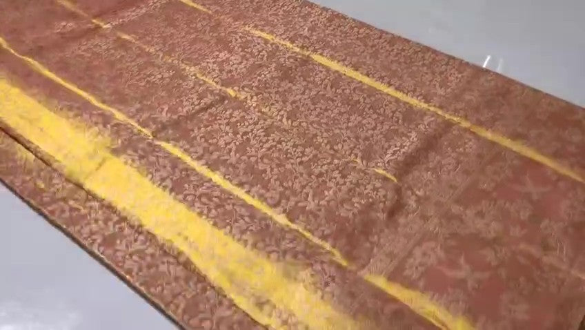 A close-up view of a Dusty Rose Kanchipuram tissue silk saree featuring elegant gold floral brocade patterns and authentic handloom texture.