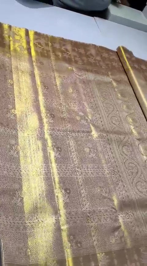 A close-up of a luxurious gold Kanchipuram tissue silk saree featuring intricate metallic brocade weaving, authentic Silk Mark certification, and a grand bridal luster.