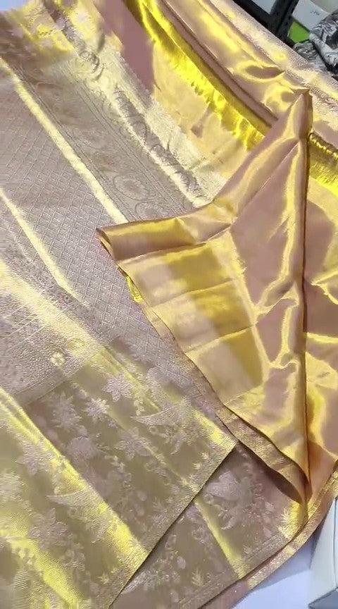 A close-up of a luxurious gold Kanchipuram tissue silk saree featuring intricate metallic brocade weaving, authentic Silk Mark certification, and a grand bridal luster.